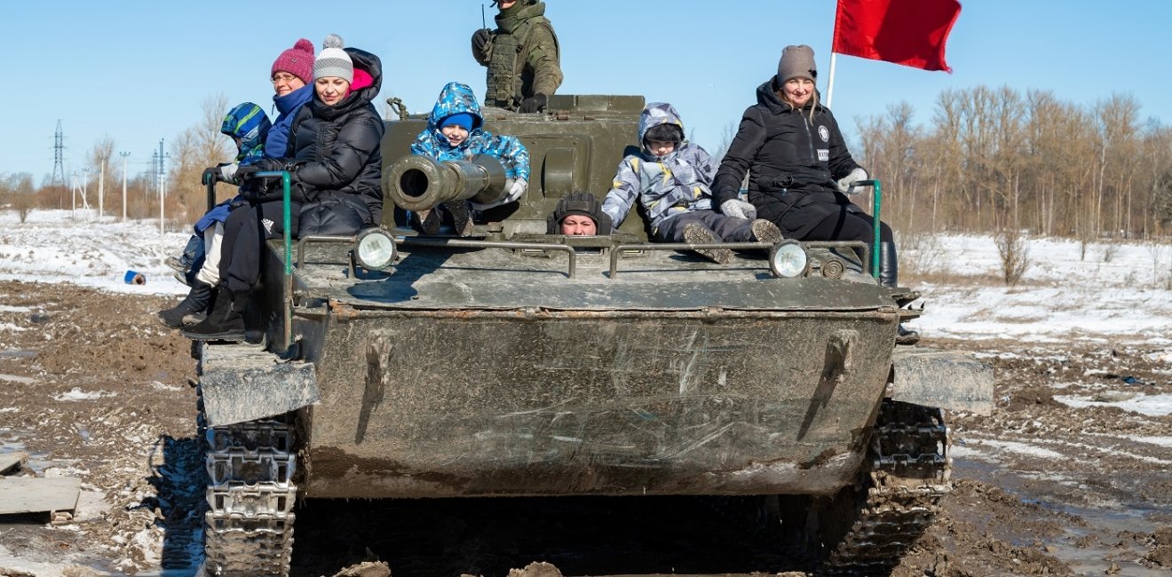 Visitors with children ride in the Soviet amphibious tank of PT-76 on a sunny March day.