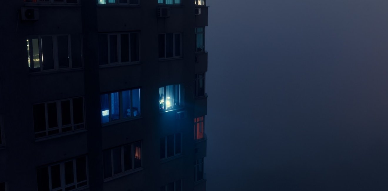 Person shining flashlight from a dark apartment building 