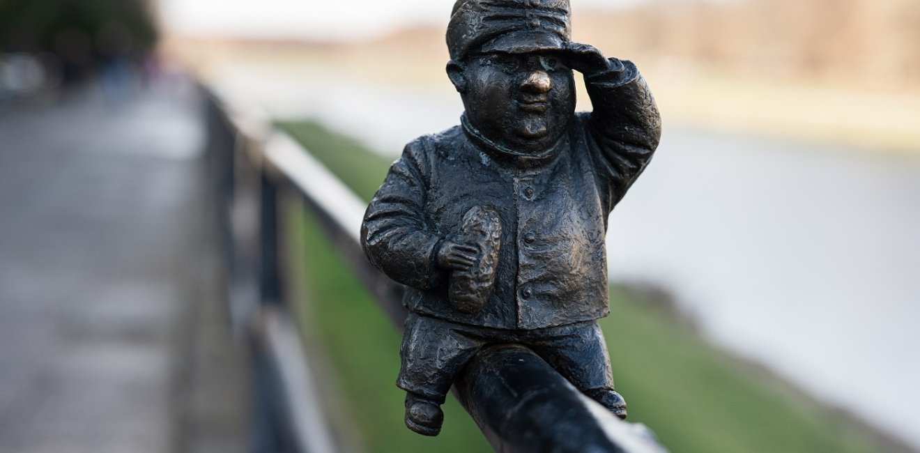 Small metal statue sitting on a fence 