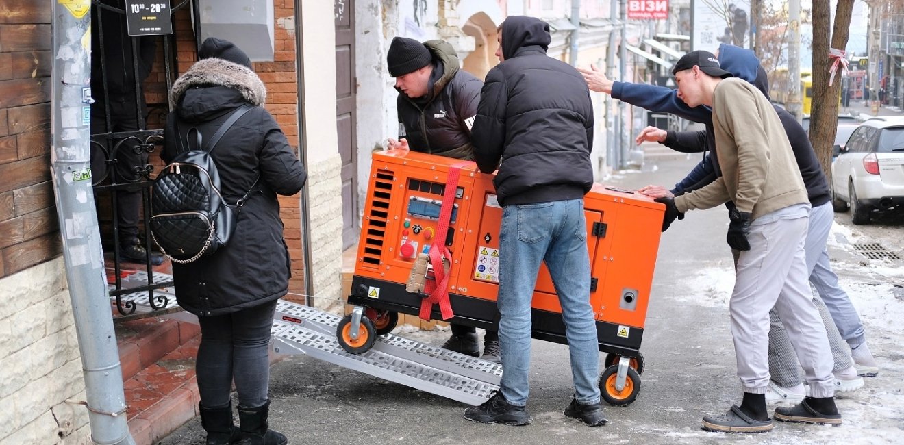 Group of men bringing an orange generator through a doorway