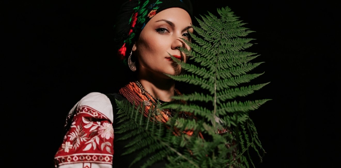 A woman in traditional Ukrainian handkerchief and vyshyvanka holding a leaf.