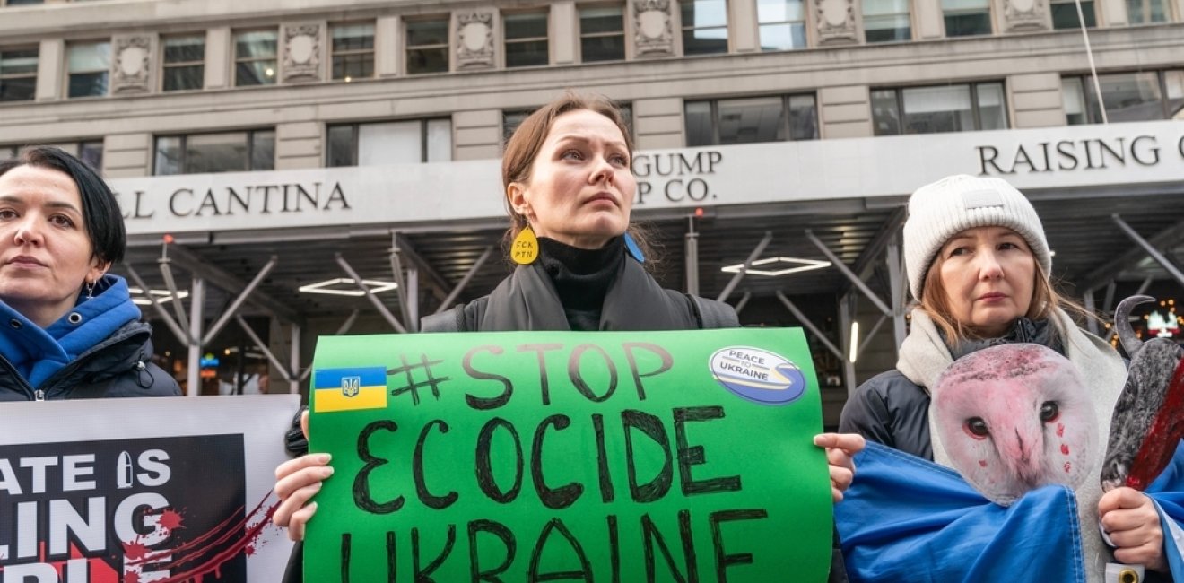 Woman holding sign with "Stop Ecocide Ukraine" written on it 