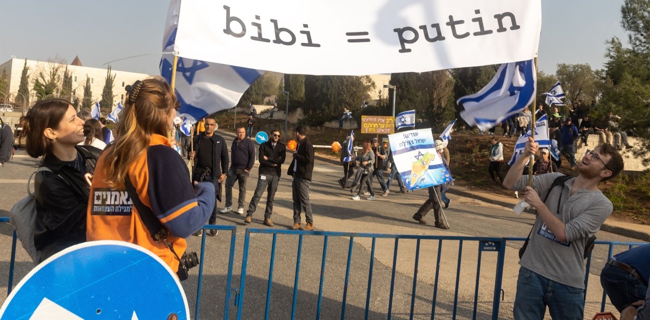 Protesters carrying sign comparing Netanyahu and Putin