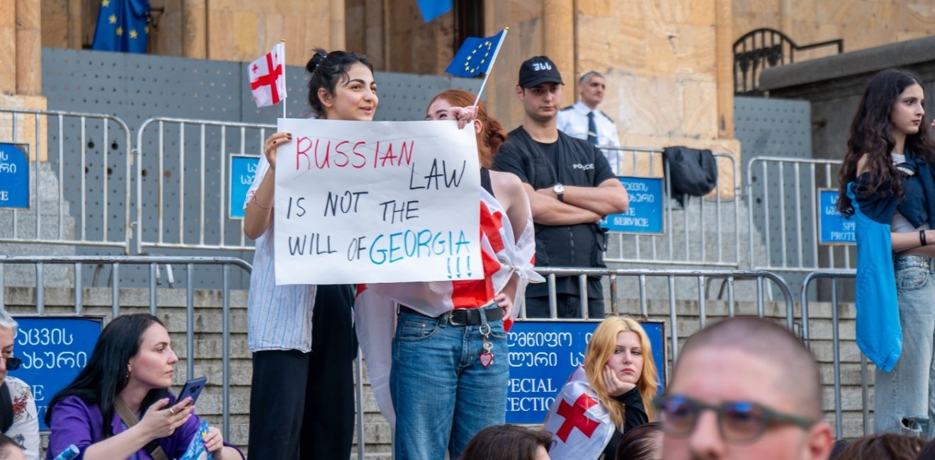 Protesters at Georgian parliament building in Tbilisi with flags and placards