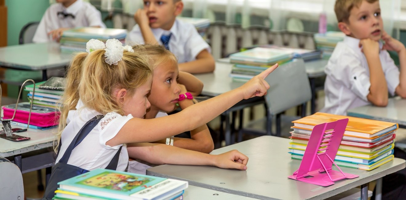 Odessa, Ukraine - September 1, 2015: elementary school students at their desks with textbooks on the first day of the school year. Feast Day of Knowledge. Beginning of a new academic year.