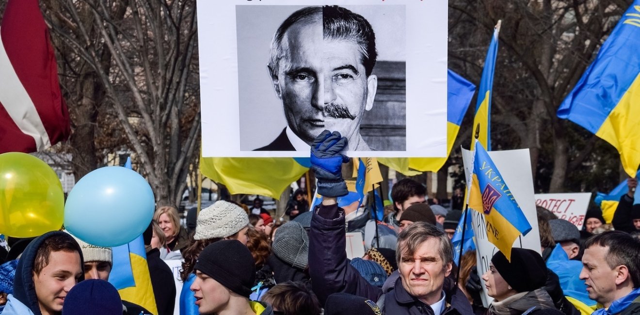 Protest with Ukrainian flags and poster comparing Putin to Stalin 