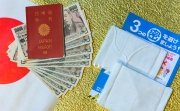 Cloth masks, a leaflet, and 100,000 yen cash sitting on a background with a Japanese flag.