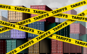 Yellow tape that reads 'tariffs' crosses in front of shipping containers