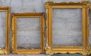 Three golden frames leaning against a wall