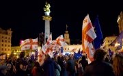 A crowd of protesters in front of the monument in Liberty Square in Tbilisi wave Georgian flags and EU flags. 