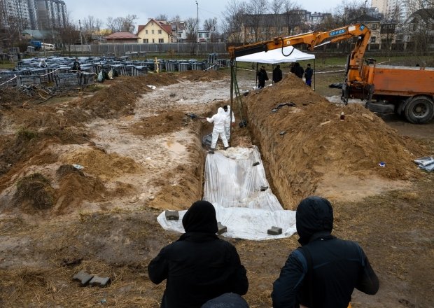 Forensic experts are working to dig up bodies from a clandestine grave found behind a church in the town of Bucha.