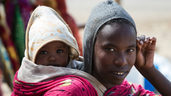 Ethiopian young woman with baby on the back on Addis Ababa Street by Andrzej Kubik/Shutterstock