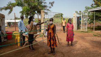 A South Sudanese refugee has her temperature checked before entering a health centre in Uganda’s Bidibidi refugee settlement. © UNHCR/Esther Ruth Mbabazi