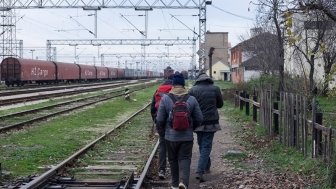 Migrants walking along train tracks in Serbia. Source: Shutterstock.