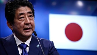 Prime Minister Shinzo Abe speaks at an event with the Japansese flag in the background.