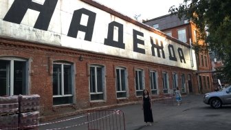 Kathryn David stands in front of a large sign that reads "hope" in Russian