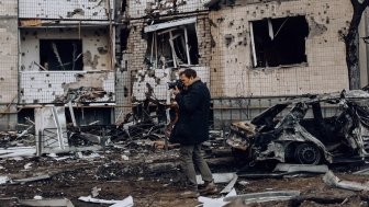 photographer in front of a bombed building in Kyiv, Ukraine