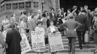 Women on steps holding signs "No Nuclear Arms for Canada