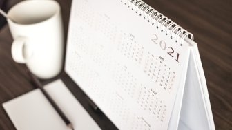 A coffee mug sits next to a desk calendar that shows the year 2021