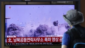 A man watching a TV screen showing a news program with a video of the demolition of the inter-Korean liaison office building in Kaesong, North Korea.