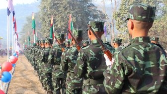 A line of men in camouflage face away from the camera.