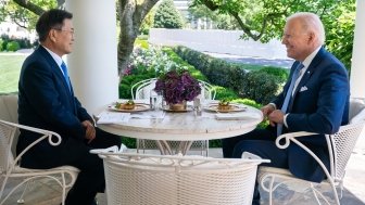 President Moon Jae-in sits opposite of President Joe Biden at an outdoor table.