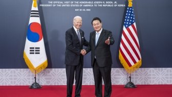 President Biden and President Yoon shaking hands in front of a banner announcing the official visit in 2022.