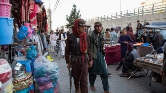 Two men who appear to be soldiers are walking through a crowded market.