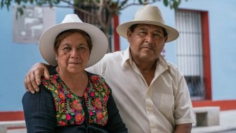 Latin couple of grandparents, sitting outdoors in colorful streets of Oaxaca, Mexico.