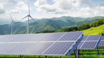 Solar panels and wind turbines against mountain landscape.