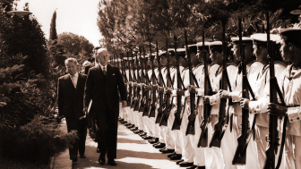 George F. Kennan stands before a line of soldiers