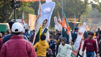 Indian citizens parade in the street holding India flags and images of President Modi