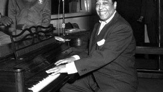 Duke Ellington, a famous jazz musician, poses with his piano at the KFG Radio Studio.