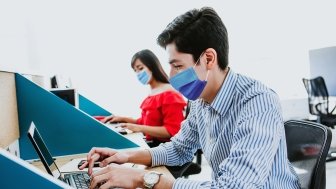 Workers with face masks at computers.