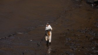 Callao, Peru; January 19, 2022: Workers clean after an oil spill, on Cavero Beach in the Ventanilla district of Callao. From La Pampilla Repsol refinery