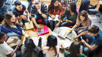 Students gathered around tables speaking with one another