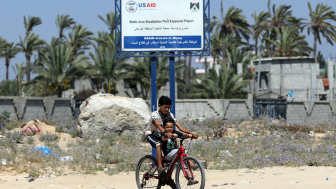 TWO BOYS ride a bike past a USAID sign last week announcing a desalination plant project in the Gaza Strip.