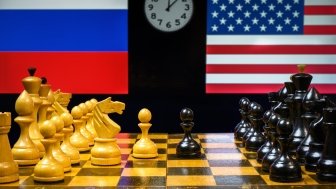 Chess board in foreground, US and Russian flags in background