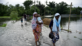 People wade through flooded road at flood effected Kalgachi in Barpeta.