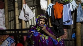 Bangladeshi woman sitting in front of clothing lines