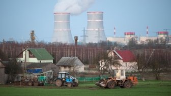 tractors work against the backdrop of a nuclear power plant