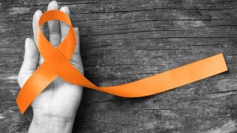 Orange ribbon in hand for raising awareness of multiple sclerosis