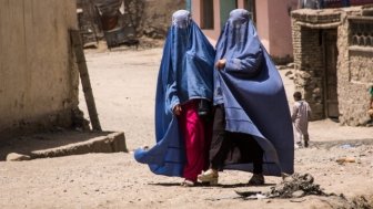 Afghan women in burqas walking in the street in Kabul, timsimages.uk/Shutterstock.com; End War in Afghanistan protest from local diaspora in Ottowa, Canada.