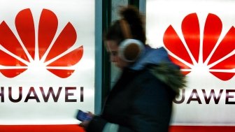 A young woman walks past to advertisement light boxes with Huawei logo in Kiev, Ukraine.