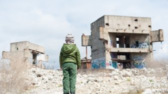 image of young boy looking over a bombed-out building 