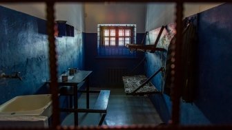 Empty prison cell in Russia. Two beds, a table, a washstand and a toilet are behind bars.