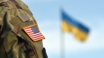 American soldier stands in front of the Ukrainian flag