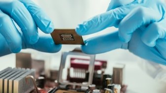 partial view of engineer holding microchip near computer motherboard