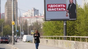 April 17 2020: Girl in a mask on a city street and a banner with the image of the mayor of Kyiv, sign reading "Do not go" in the Ukrainian language