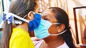 Mother and child touch noses while wearing face masks.